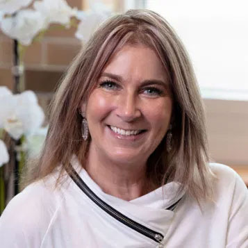 The image shows a woman with short hair smiling at the camera she s wearing a white top with a black collar, and there are two photos of her side by side.